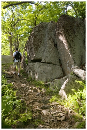 The trail is rocky and passes many large boulders.